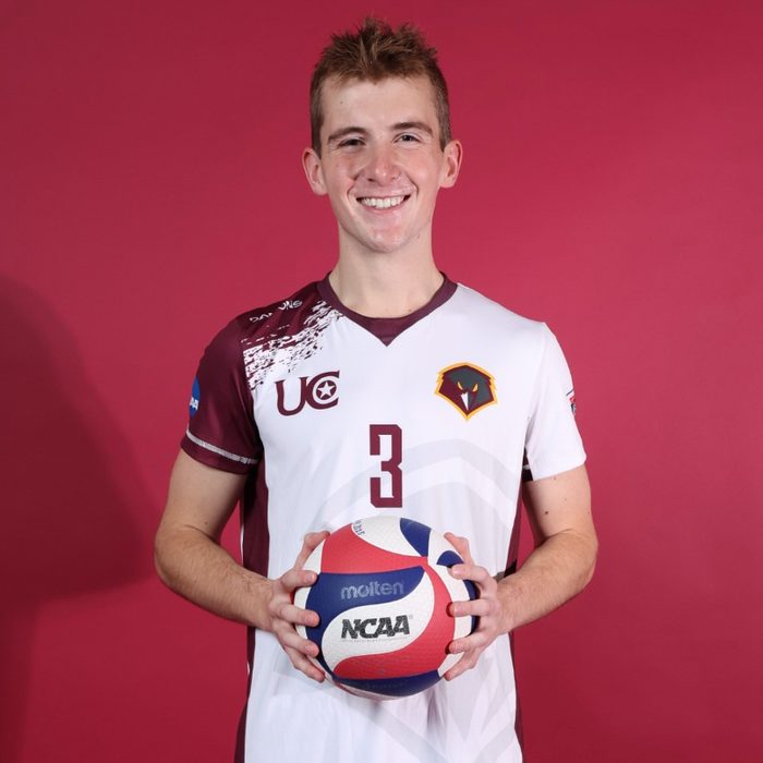 Tyler Roukey holding a volleyball in his team uniform